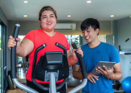 Asian fat woman workout with her trainer for exercise and diet in fitness center clubの写真素材