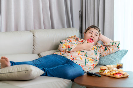 Asian over size fat woman enjoy over eating on the living room, un healthy foods and junk food concept photoの写真素材