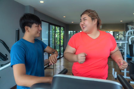 Asian fat woman workout with her trainer for exercise and diet in fitness center clubの写真素材