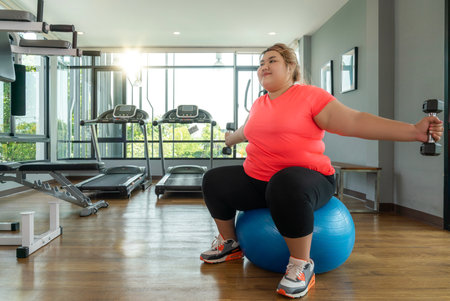 Asian fat woman workout with her trainer for exercise and diet in fitness center clubの写真素材