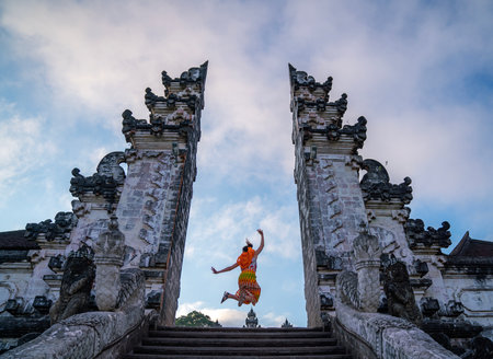 Indonesia gate in temple in Bali with indonesian woman with morning sunrise skyの写真素材