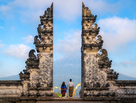 Indonesia gate in temple in Bali with indonesian woman with morning sunrise skyの写真素材