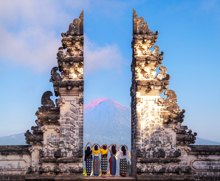 Indonesia gate in temple in Bali with indonesian woman with morning sunrise skyの写真素材