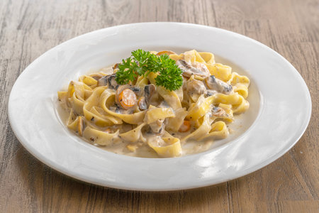 mushroom cream sauce spaghetti on white dish put on the wooded table in italian restaurantの写真素材