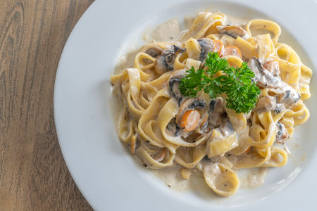 mushroom cream sauce spaghetti on white dish put on the wooded table in italian restaurantの写真素材