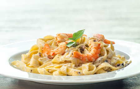 mushroom cream sauce spaghetti with shrimp on white dish put on the wooded table in italian restaurantの写真素材