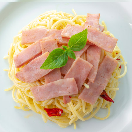 Spaghetti aglio e olio, pasta with chili and garlic and Ham on white plateの写真素材