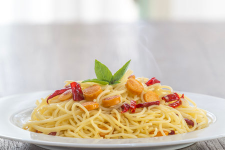 Spaghetti aglio e olio, pasta with chili and garlic, sausage and bacon on white plateの写真素材