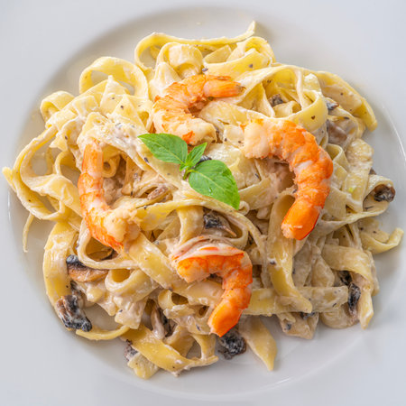 mushroom cream sauce spaghetti with shrimp on white dish put on the wooded table in italian restaurantの写真素材