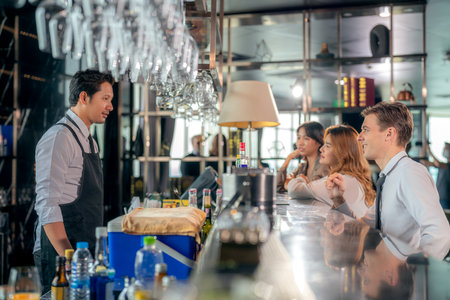 Asian man bartender and his customer talking in roof top bar and  restaurant with beverage counterの写真素材