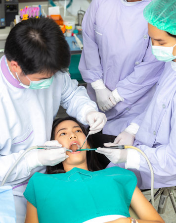 Asian woman decayed tooth operation in dental clinic with her dentist, Doctor and professional dental team in hospitalの写真素材