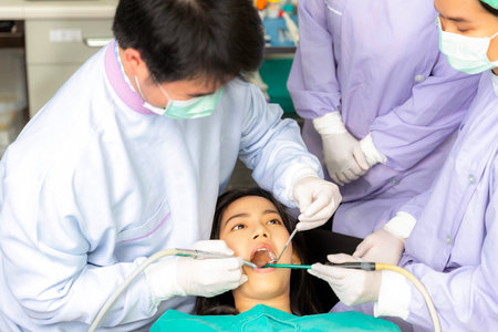 Asian woman decayed tooth operation in dental clinic with her dentist, Doctor and professional dental team in hospitalの写真素材