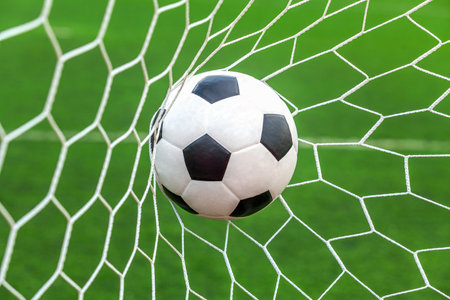 soccer ball on goal with net background, football player shoot a leather foot ball for make a scoreの写真素材