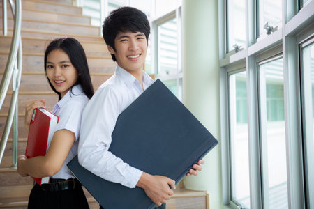 Asian woman and man student read text book in her university library for learning and doing home workの写真素材