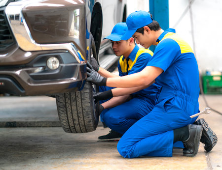 repairman and technician in car garage service in blue uniform standup and smile with tooling on hand for car check and maintenanceの写真素材