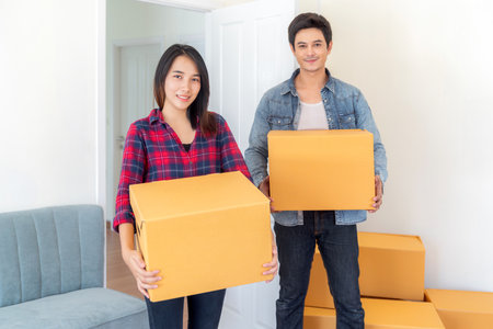 Asian couple just new married husband and his wife carry a paper box togather on stairs for move it to home second floor for move in to new house and start fot new sweet familyの写真素材