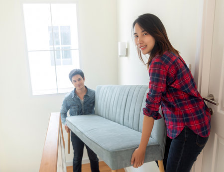 Asian couple just new married husband and his wife carry a sofa togather on stairs for move it to home second floor for move in to new house and start fot new sweet familyの写真素材