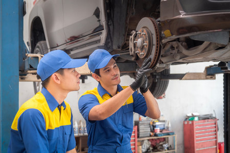 repairman and technician in car garage service in blue uniform standup and smile with tooling on hand for car check and maintenanceの写真素材