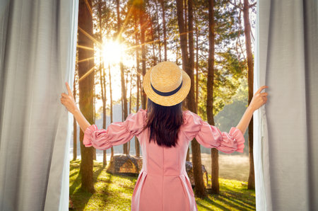 Asian woman traveller open curtain of hotel room for see view after arrival to Doi and  mountain resort in Chiang mai, Thailandの写真素材