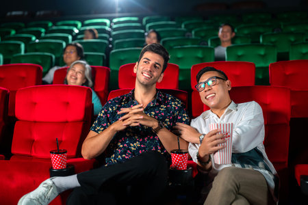 gay couple sweet and watching cinema together on red seat in theater, lgbt couple travel and relax in valentine dayの写真素材