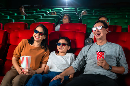 Asian family relax and fun togather by watching 3d action cinema in theater, father mother and daughter holiday in weekend with action movieの写真素材