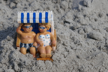 Happy couple makes beach holiday. Man and woman are sitting happily smiling in a beach chair by the sea.の写真素材