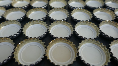 Bottle caps, side by side on black background. Collage of many small bottle caps, beer bottle caps, metal bottle caps. Closeup, texture, backgroundの写真素材