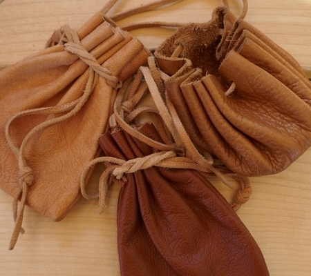 Three brown leather pouches with ribbon, close-upの写真素材