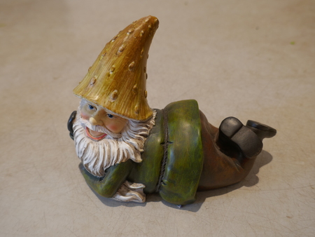 Garden gnome reads on his stomach and laughs. Close-up. Isolated against neutral backgroundの写真素材