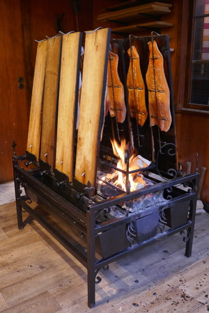 Finnish flame salmon on wooden boards in a wrought iron grill at the open charcoal fireの写真素材