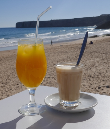 Freshly squeezed orange juice and a glass of latte in a small beach bar overlooking the seaの写真素材