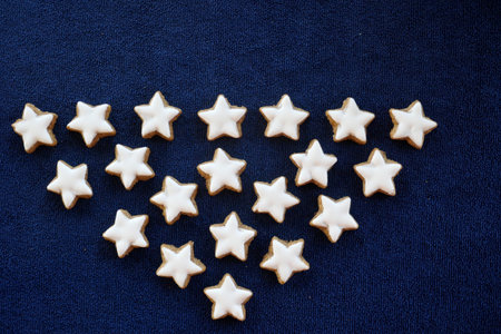 Many home baked cinnamon stars isolated in front of dark blue background.