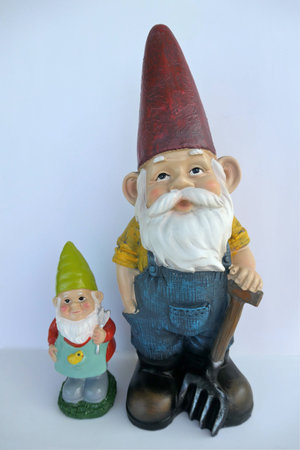2 garden gnomes, a small and a big one, isolated on white background.Front view, close-up. Farmer...
