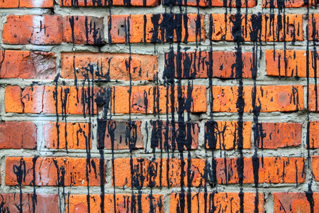 Background the laying of red bricks covered with black stripes of black oil