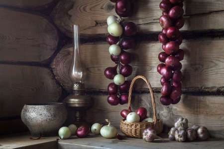 Still life with an old kerosene lamp, pot, red onion and garlic in a country houseの写真素材