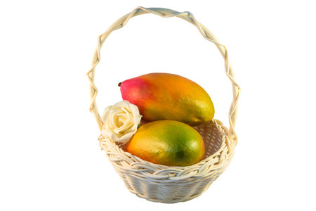 Two red and yellow mangoes in a basket on white isolated background. Ripe fruit. Beautiful exotic fruits. Dietary food. Delicious dessert food. Wicker basket made of twigs with a long handle.の写真素材