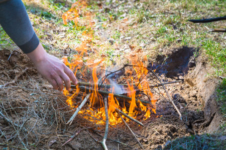 Safely lighting a fire in the forest countryside. Rural place. Dug a fire pit. Hands making a fire