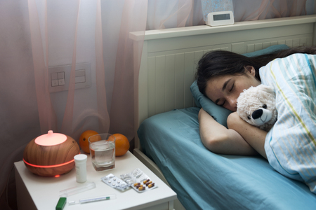 Teenage girl in bed at home caught cold, feeling bad, sleeping.の写真素材