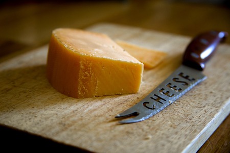 Parmesan cheese with knife on cutting board on wooden backgroundの写真素材