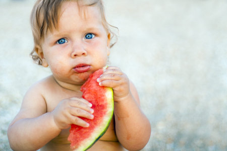 little baby eating watermelon outdoorsの写真素材