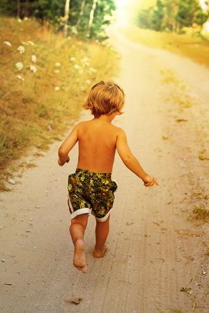 Boy running along road in park, outdoorの写真素材