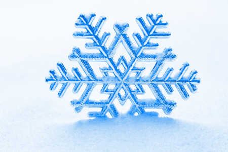 snowflake ornament against a background of snowの写真素材
