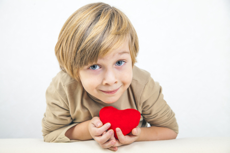 Cute young boy with a red heart in his handsの写真素材