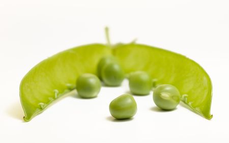Green peas in front of open pod isolated on whiteの写真素材