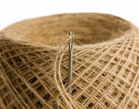 Extreme closeup of beige clew and needle isolated on white