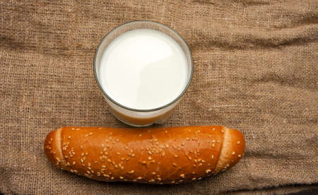 Fresh loaf and glass of milk over bagging backgroundの写真素材