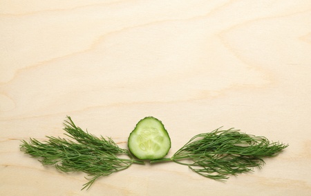 Macro of cucumber slice and dill twigs on wood backgroundの写真素材