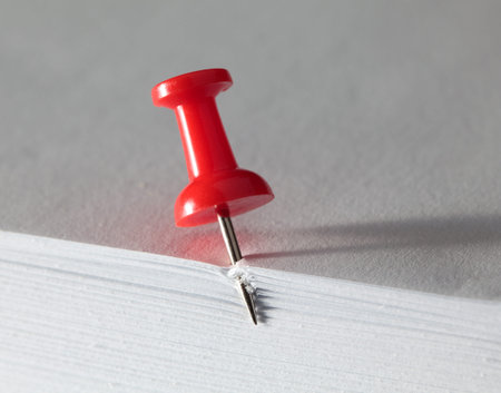 Macro of drawing pin punctured blank paper pile