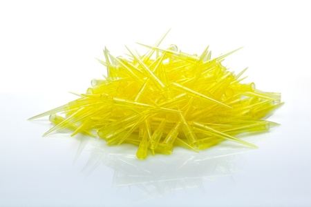 Closeup of yellow disposable tips for laboratory pipette on white reflective planeの写真素材