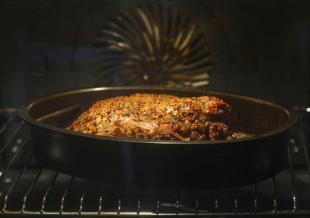 Close-up of golden roasted steak sprinkled with spices in baking tray in electric ovenの写真素材